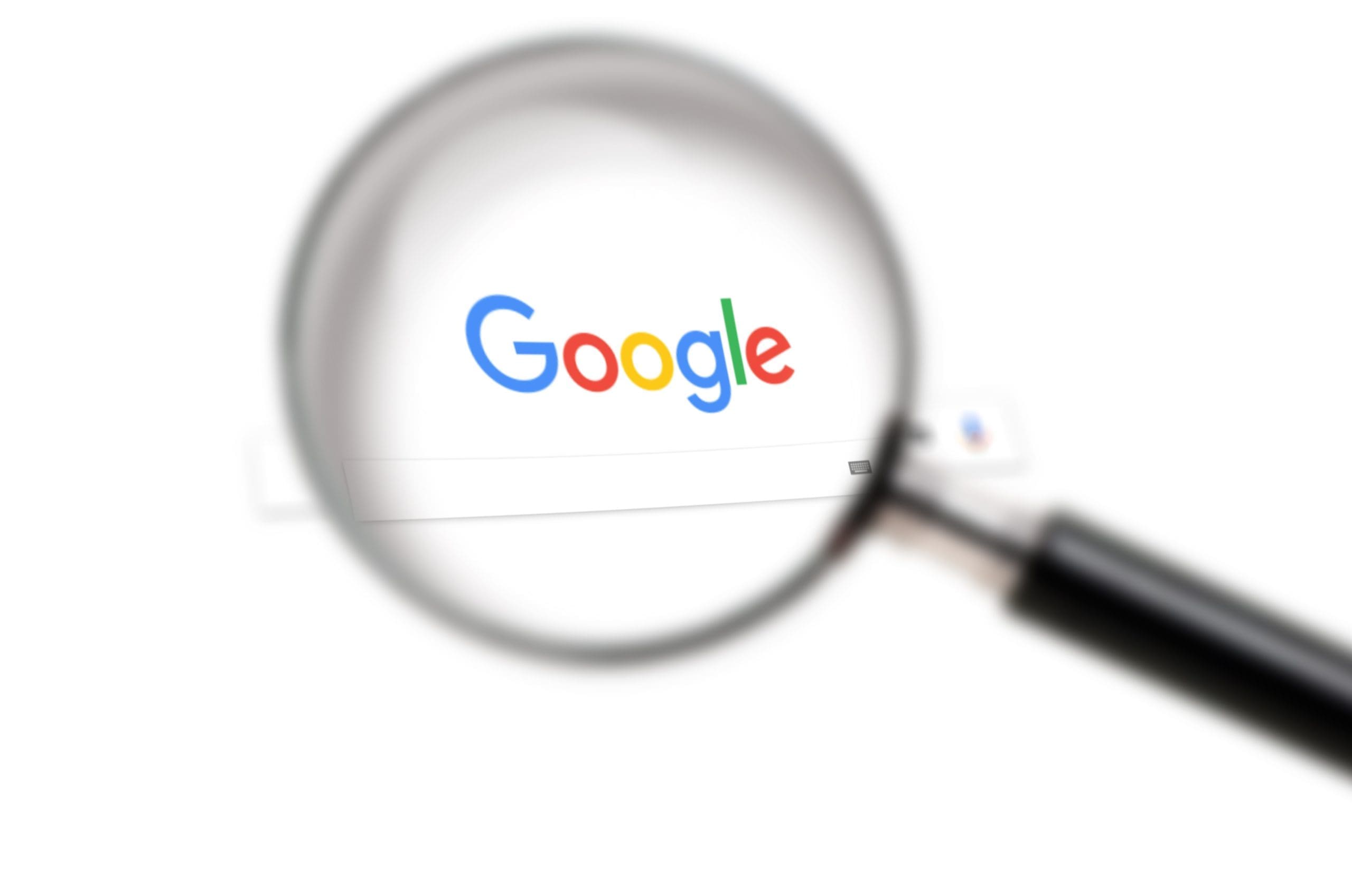 Google logo under a magnifying glass.