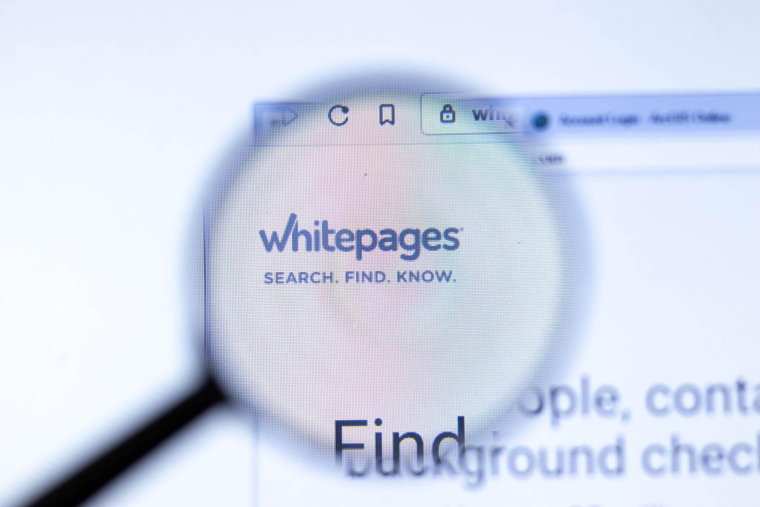 A magnifying glass is shown over the whitepages website.