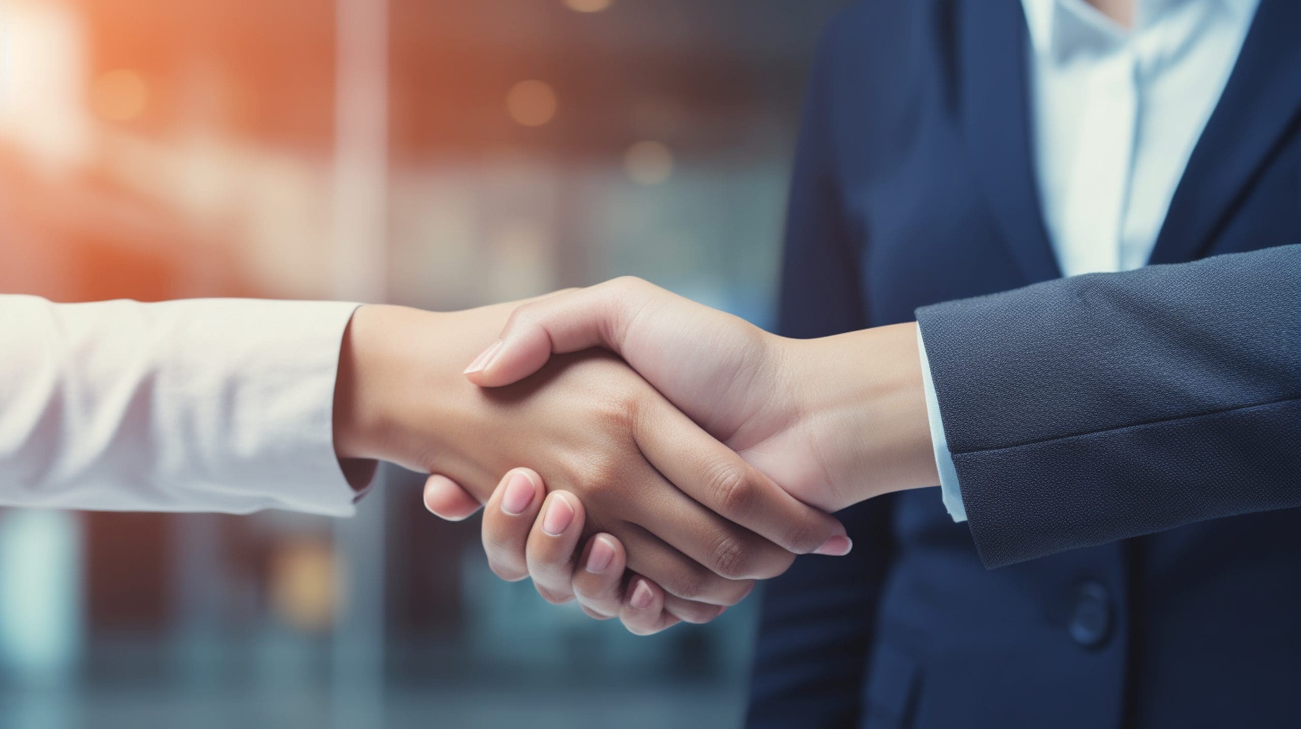 Two business people shaking hands in front of an office.
