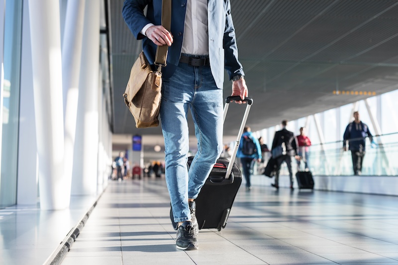 A person walks through an airport rolling luggage.